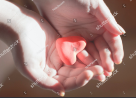 Photograph of little heart shaped object placed in a person's hand.